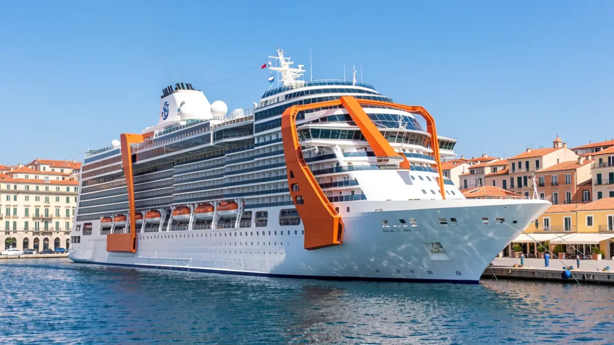 The cruise ship Celebrity Apex docked in the port of Malaga, highlighting its orange exterior elevator.