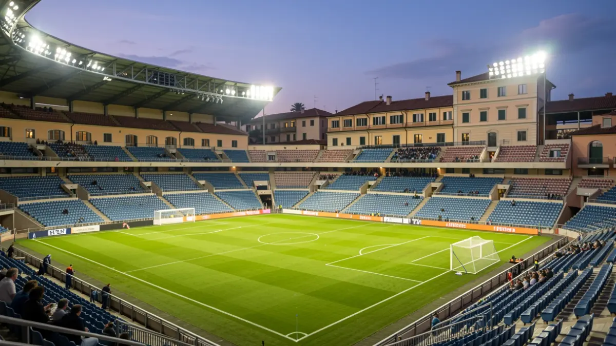 Football stadium illuminated at dusk, with empty seats and green grass.