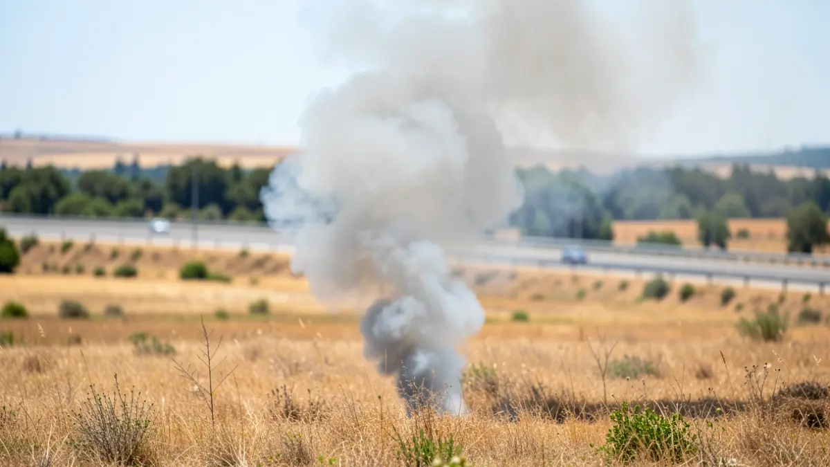 Imagen genérica de una columna de humo de un incendio de pastos visible desde una autovía.