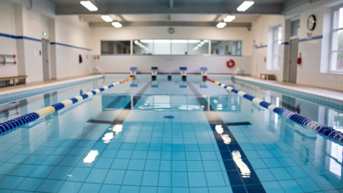 Generic image of the interior of an indoor swimming pool with empty lanes and blue tiles.