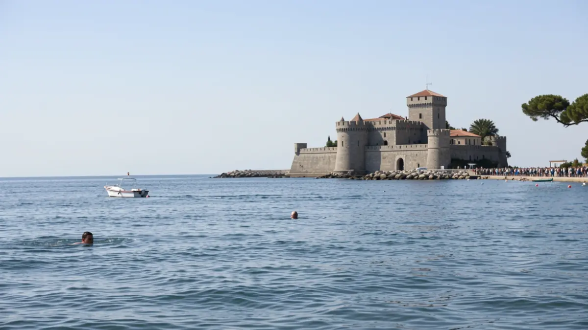 Nadador en el mar cerca del Castillo de Sancti Petri, con una embarcación de apoyo.