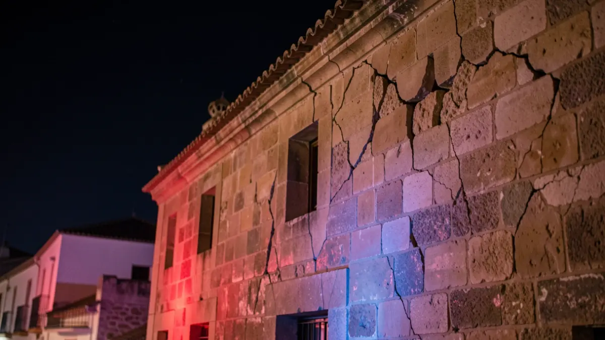 Cracked building facade in Andalusia after an earthquake, with emergency lights.