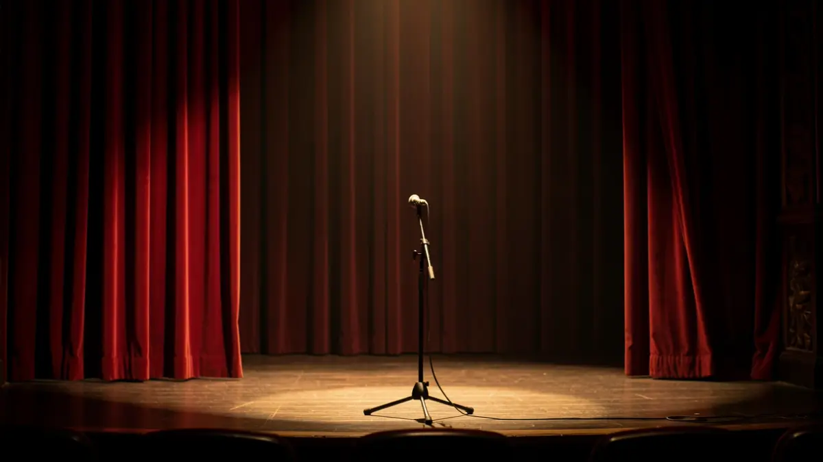 Generic image of a theatre stage with a microphone and velvet curtains.