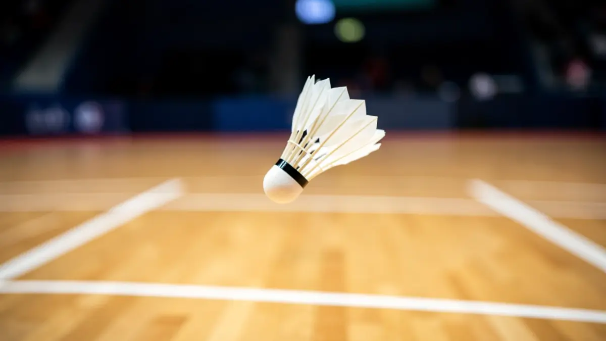 A badminton shuttlecock in mid-flight over a sports court.