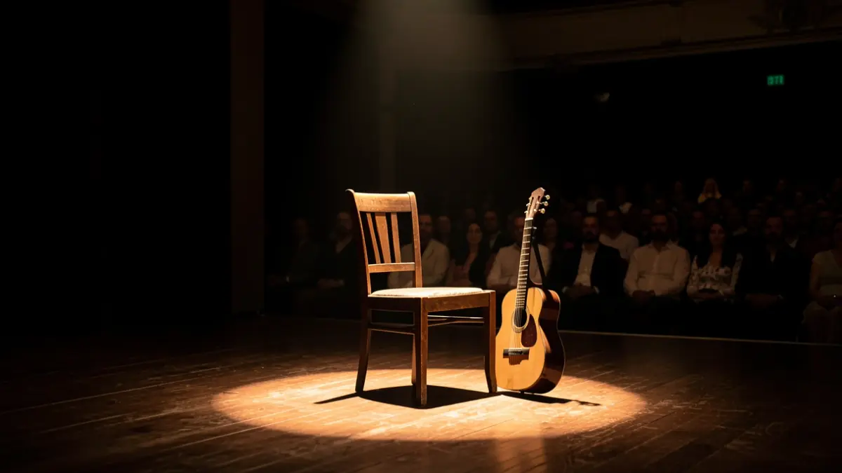 Escena de un escenario de flamenco vacío con una silla y una guitarra.